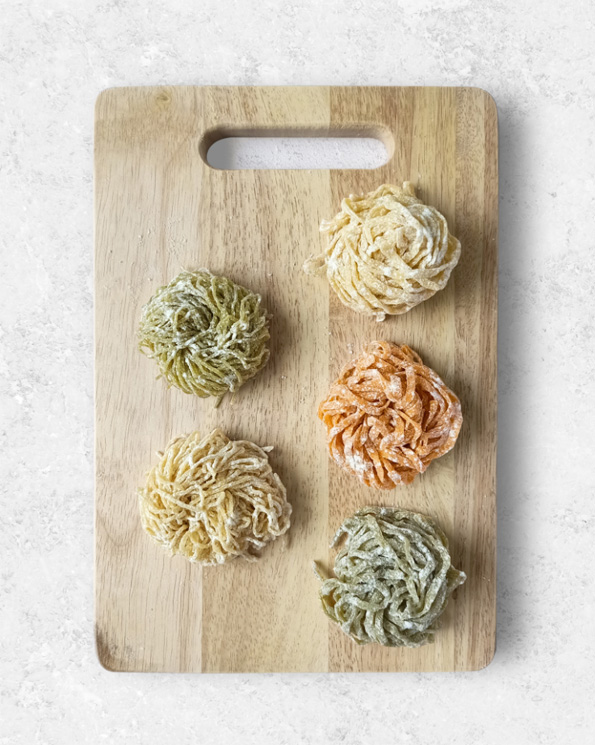 fresh egg noodles and fresh pasta on a chopping board เส้นบะหมี่ไข่สดและเส้นพาสต้าสดจัดวางบนเขียง