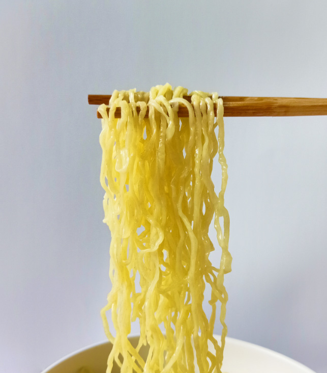 cooked Free-ranged Egg Noodle in a white bowl เส้นบะหมี่ไข่สดจากไข่แม่ไก่อารมณ์ดีลวกสุก