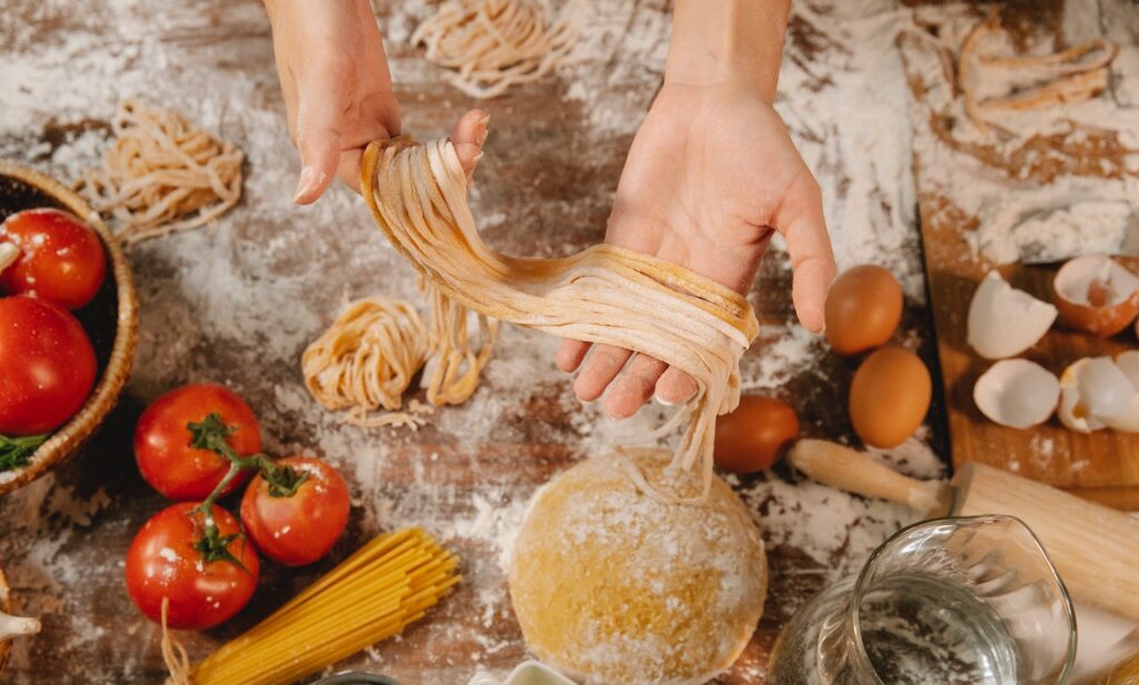 a woman preparing fresh pasta for a family meal หญิงสาวกำลังเตรียมเส้นพาสต้าสดสำหรับมื้ออาหารของครอบครัว