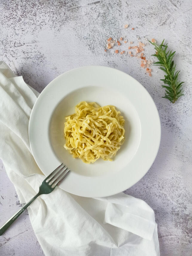 plating cooked free-ranged egg linguine pasta in a white plate เส้นพาสต้าลิงกวินีสดจากไข่แม่ไก่อารมณ์ดีลวกสุกในจานสีขาว