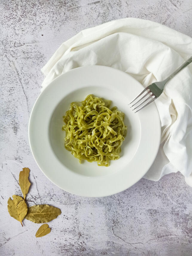 plating cooked organic spinach linguine pasta in a white plate เส้นพาสต้าลิงกวินีสดผสมผักโขมออร์แกนิคลวกสุกในจานสีขาว