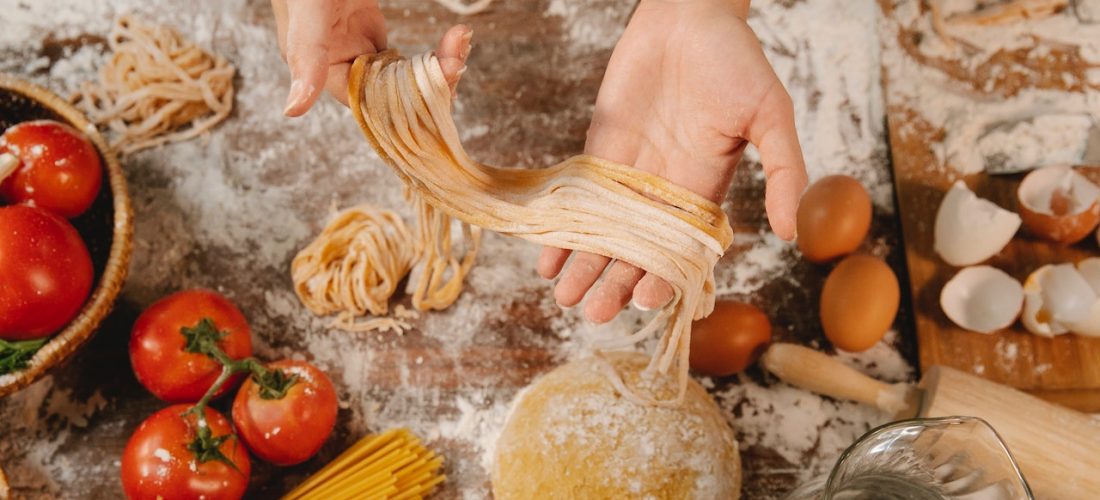 a woman preparing fresh pasta for a family meal หญิงสาวกำลังเตรียมเส้นพาสต้าสดสำหรับมื้ออาหารของครอบครัว